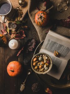 Imagen otoñal con libros y vela que evoca calma y autocuidado